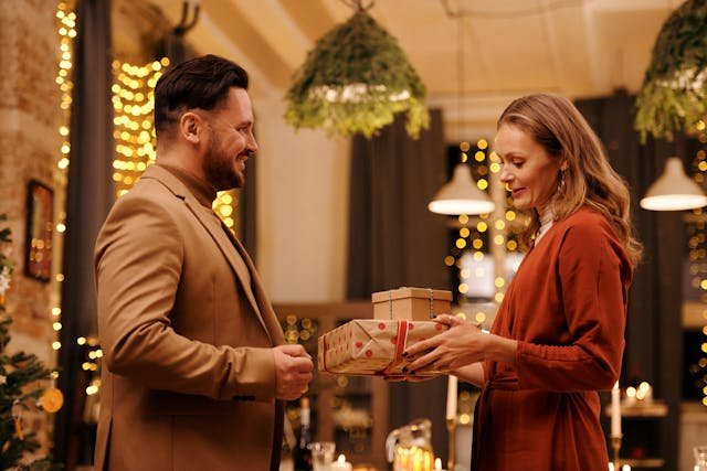 Couple exchanging anniversary gift ideas for men in a romantic decorated setting