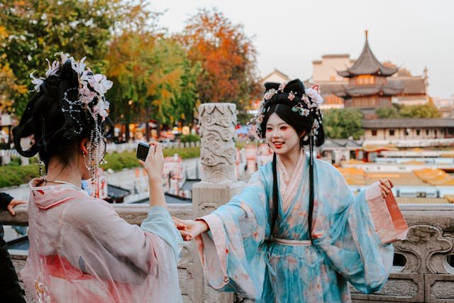Two women wearing Chinese traditional clothing hanfu with floral hair accessories at a historic Chinese pagoda