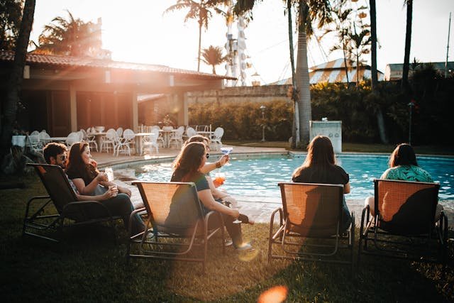 Groups of friends enjoying the best beach resorts in USA poolside at golden hour with palm trees and tropical landscaping