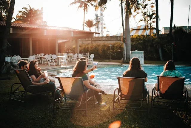 Groups of friends enjoying the best beach resorts in USA poolside at golden hour with palm trees and tropical landscaping