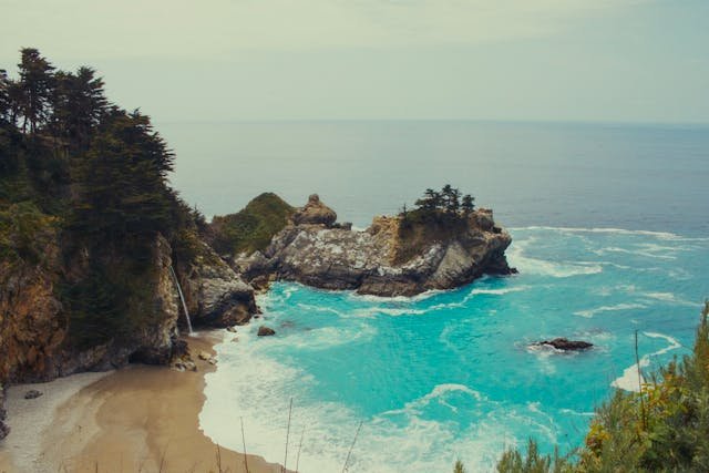 Turquoise water and McWay Falls cascading onto a secluded sandy cove at Pfeiffer Beach, Big Sur, California west coast