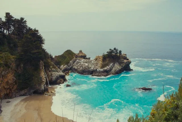 Turquoise water and McWay Falls cascading onto a secluded sandy cove at Pfeiffer Beach, Big Sur, California west coast